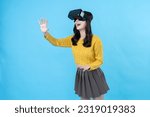 Asian woman with long hair Put on 3D VR glasses about the virtual world of gamers. Turn sideways, raise your hands, put on a yellow coat and skirt. Taking photos in the blue screen studio