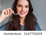 Young beautiful  woman holding dental aligner orthodontic to tee