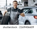 Workman at car repair shop changing tires