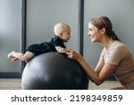 Mother with baby daughter exercising with yoga ball