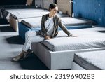 Small photo of Woman lying on bed with orthopedic pillow in furniture store