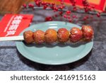 Small photo of A plate of tasty candied haws with four Chinese characters on red paper that translation means "candied haws" and a big characters in the backgroud which means 'happiness' in English.