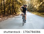 Professional sportsman in active wear and protective helmet drinking water while riding bike on fresh air. Mature man in mirrored glasses enjoying favorite hobby during summer time.