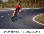 Muscular young guy wearing sport clothing, protective helmet and mirrored glasses enjoying sport activity on black bike. High speed and racing.