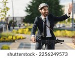 Small photo of Happy male office clerk gesturing, saying hi to workmate on street. Front view of bearded caucasian manager greeting colleagues, while getting to work by bike in morning. Concept of greeting gesture.