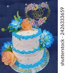 Small photo of 2 tier wedding cake bottom 10” 3 layers chocolate with whip cream filling top 8” 3 layers chocolate with whip cream filling whip cream icing Deco: combination of real and silk flowers and leaves
