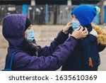 Mother puts her child a face protective mask on the street. Stop the infection. Coronavirus quarantine. Apocalypse. Health care concept. Mask against infectious diseases and flu.