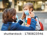 Small photo of Father helping son and putting on face protective mask. Little boy going to school during coronavirus pandemic. Businessman father and son going to school. Schoolboy is ready go to school.