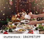 hands of woman holding Christmas Eve wafer at the festive table with traditional dishes