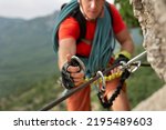 Small photo of Climber snaps the safety carabiner on the rope. A climber on a cliff ties a safety knot