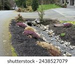 Small photo of Landscaping of a drainage ditch running through a driveway culvert, water meter in view