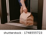 Contactless food delivery from restaurant. New normal. Coronavirus covid-19 reality. Order dinner online. No dining in. Quarantine life. Recycle paper bag. Chinese meal. Man holds bag apartment door.