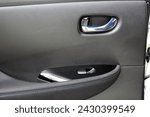 Small photo of Electric Car door trim with windows control. Car Inside Door Handle Interior. Leather Door trim. Rear door trim of a Electric car. Electric Car interior.
