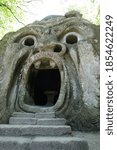 Small photo of Bomarzo, Viterbo, Lazio / Italy - 08/25/2020: Orcus mouth sculpture at famous Parco dei Mostri (Park of the Monsters), also named Sacro Bosco (Sacred Grove) or Gardens of Bomarzo in Bomarzo