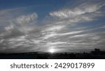 Small photo of White sun below with white greyish clouds covering the sky. Below sky is urban settlements houses and trees.