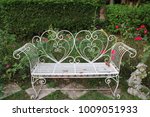 White steel chair with double heart shape near the rose tree and have little girl statue  in the garden