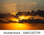 Two layers of clouds with sun shining behind leaving beautiful rays of sun from behind. Dramatic sunset sky with vibrant colors.