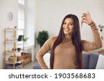 Small photo of Happy woman holding keys to new home, looking at camera and smiling. Portrait of first time buyer, house owner, apartment renter, flat tenant or landlady. Moving day and buying own property concept