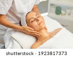 Hands of cosmetologist making manual relaxing rejuvenating facial massage for young woman in beauty salon. Rejuvenating facial massage in cosmetology