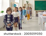 Small photo of Elementary students leaving classroom. Happy kids entering study room together. Small group of cute little children in casual clothes walking in single file out of classroom after class is over