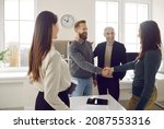 Small photo of Happy business people meeting in a modern office. Two colleagues making an acquaintance and greeting each other. Friendly man and woman shaking hands after their coworkers have introduced them