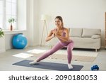 Small photo of Maintaining good physical condition. Slender beautiful young woman performs sports exercises during morning workout at home in living room. Concept of daily training, maintaining good body and health.