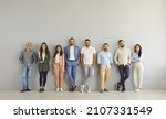 Small photo of Full body portrait of happy business people in smart and casual clothes. Full length group of senior and young Caucasian men and women posing against grey studio wall. Clothing and fashion concept