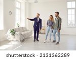Real estate agent giving potential buyers or future tenants tour about big new house. Boyfriend and girlfriend or husband and wife who plan property investment looking at lovely modern spacious home