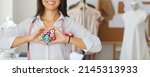 Small photo of Crop narrow banner of woman seamstress or tailor show love heart hand gesture or sign with threads. Smiling female dressmaker or designer feel affectionate about fashion atelier business.