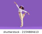 Small photo of Happy kid poses in trendy casual outfit. Beautiful child having fun in fashion studio. Pretty Black girl wearing purple beret, lilac top and beige denim pants standing on one foot on purple background
