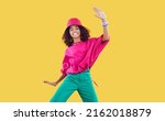 Small photo of Happy joyful Black kid in funky outfit dancing in studio. Cheerful African dancer girl wearing loose fuchsia top, bucket hat and green pants enjoying hype and having fun. Children's fashion concept