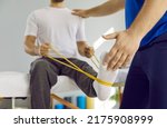 Small photo of Male patient using elastic band while doing physical exercises for leg muscles at modern clinic, rehabilitation center or hospital. Close up of man's foot. Physiotherapy concept