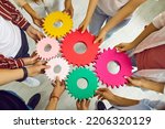 Small photo of Team of people connecting gears. Cropped shot group of young men and women standing in circle and joining colorful cogs together. Teamwork, integration, business, education, success concept background