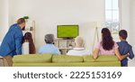Small photo of Big multi-generational family cheering while watching soccer match on TV at home. Rear view of older and younger family members and children sitting together on sofa in front of TV. Web banner.