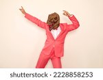 Small photo of Weird crazy guy in wacky dinosaur mask enjoying free time and having fun at party. Happy confident young man wearing funky pink suit and silly ugly dino mask dancing against background of white wall