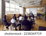 Small photo of Team of people having class with business trainer. Group of male and female employees sitting at desks in modern office and listening to lecture by experienced teacher sharing knowledge and guidance