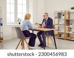 Small photo of Government authority or United States of America embassy consul discusses visa application with customer at table in office. Male Immigration Services agency worker meeting with woman who moved to USA