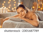 Small photo of Woman enjoying professional body massage at a modern spa salon. Relaxed young lady lying on a massage table while a skillful masseuse is gently massaging her back. Beauty, health, pleasure, concept