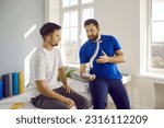 Small photo of Man professional osteopath chiropractor is consulting man showing him spine layout in hospital. They talking about backbone problems. Checkup, prevention examination, diagnosis, medicine concept.