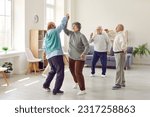 Small photo of Happy retired senior people having a party, dancing and having fun together. Elderly men and woman dancing at home or in a retirement community center. Old age and leisure concept