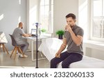 Small photo of Male patient having intravenous treatment and rehydration therapy. Young man sitting on medical couch bed, getting vitamin infusion through IV line and drinking glass of fresh water. Hydration concept