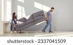 Small photo of Happy couple placing sofa in living room of new home. Smiling husband and wife carrying couch in empty living room. Family moving in new apartment or remodeling home