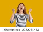 Small photo of Funny young woman overwhelmed by anger. Beautiful blonde girl in casual striped top feels very angry, frustrated, furious, mad, pissed and infuriated, clenches fists and screams with mouth wide open