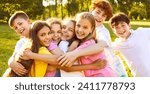 Small photo of Happy children having fun on summer vacation. Group of best friends playing outdoors together. Several little kids, girls and boys with backlit hair, hugging each other tightly in a green sunny park
