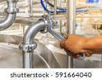 Small photo of Close up shot of a hand of technician using adjustable hook wrench during repairing pipes at mixing tank on production line in pharmacy industry manufacture factory