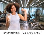 Attractive fitness African American woman finishing workout and drinking protein milk shake vitamins after training. Bodybuilding. Healthy lifestyle.