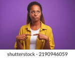Small photo of Young attractive confused African American woman in round glasses with smirk looks up has doubts thinking about job offer from company with bad reputation stands on purple studio background