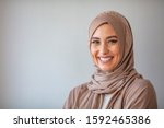 Woman in traditional Muslim clothing, smiling. Beautiful woman headshot looking at camera and wearing a hijab. Arabian woman with happy smile. Strict formal outfit and elegant appearance. Islamic