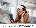Morning with gadget. Overhead of beautiful young woman lying on the bed using smartphone. Young woman checking her smart phone lying in bed. Happy girl using a mobile phone lying on the bed at home
