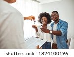 Photo of a smiling young couple thanking to the agent for the new house. Homeowners receiving their new house keys. Close up of a happy homeowners receiving their new house keys from a estate agent